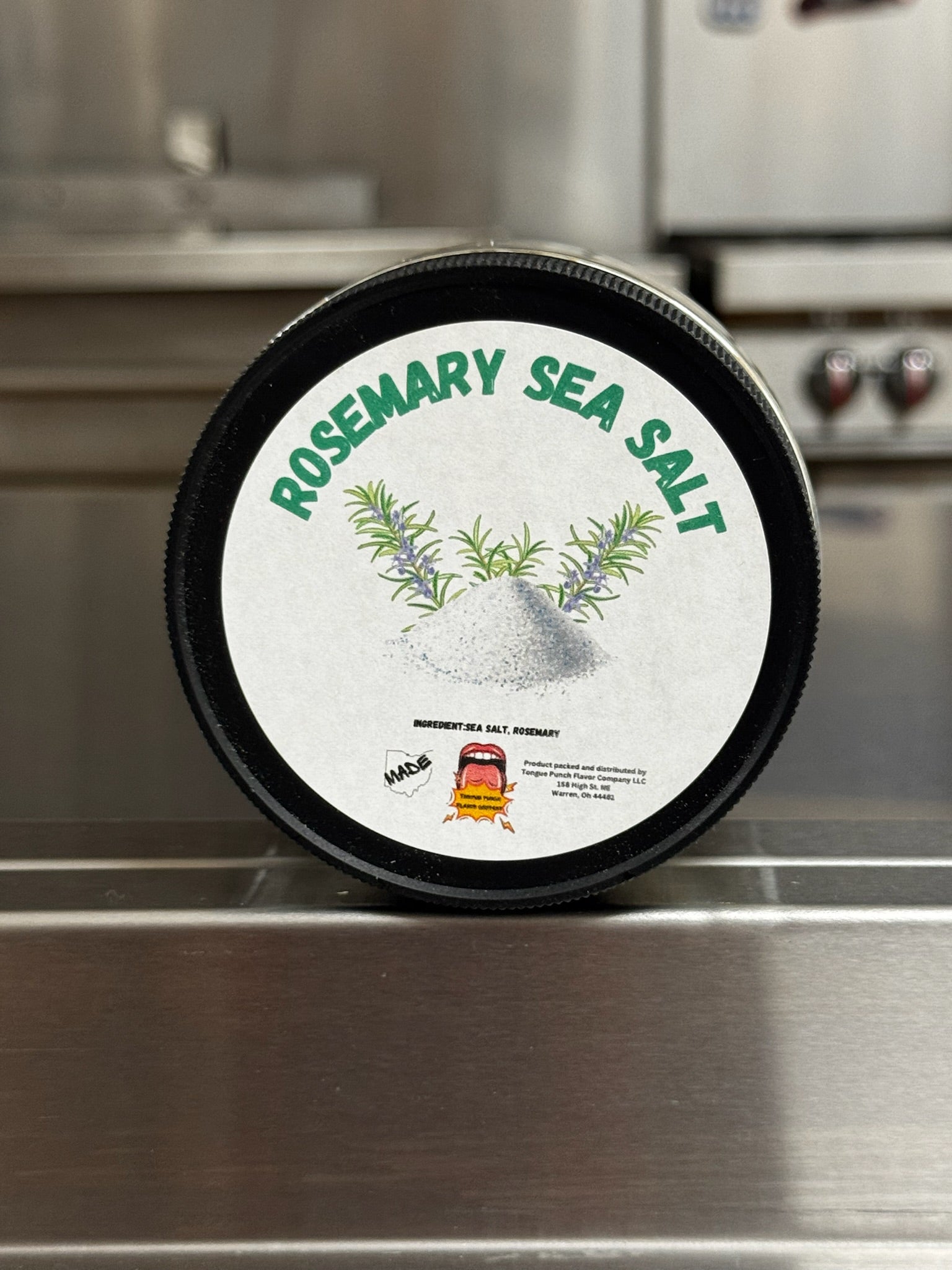 Container of rosemary sea salt on a metallic surface
